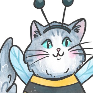May include: A gray and white cat wearing a bee costume with yellow and black stripes and blue wings. The cat has a happy expression and is looking at the viewer.
