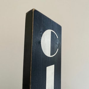 以下が含まれることがあります： 白い文字で「C I」と書いてある黒い木製の看板です。