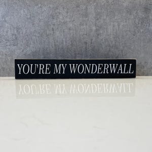 May include: Black wooden sign with white text that reads "You're my Wonderwall".