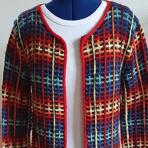Peut inclure: Un cardigan rayé rouge, bleu, jaune et orange sur fond noir. Le cardigan a un col rond et des manches longues.