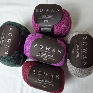 Könnte beinhalten: Fünf Knäuel Rowan Felted Tweed-Wolle in verschiedenen Farben, darunter Grün, Lila und Grau. Jedes Knäuel hat ein dunkelbraunes Etikett mit dem Markennamen und Produktdetails. Jedes Knäuel wiegt 50g.