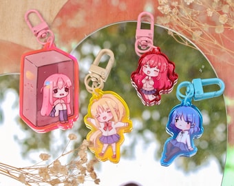 May include: Four colorful anime character keychains with different designs. Each keychain features a different character with a unique pose and expression. The keychains are made of clear acrylic and have a metal clasp.