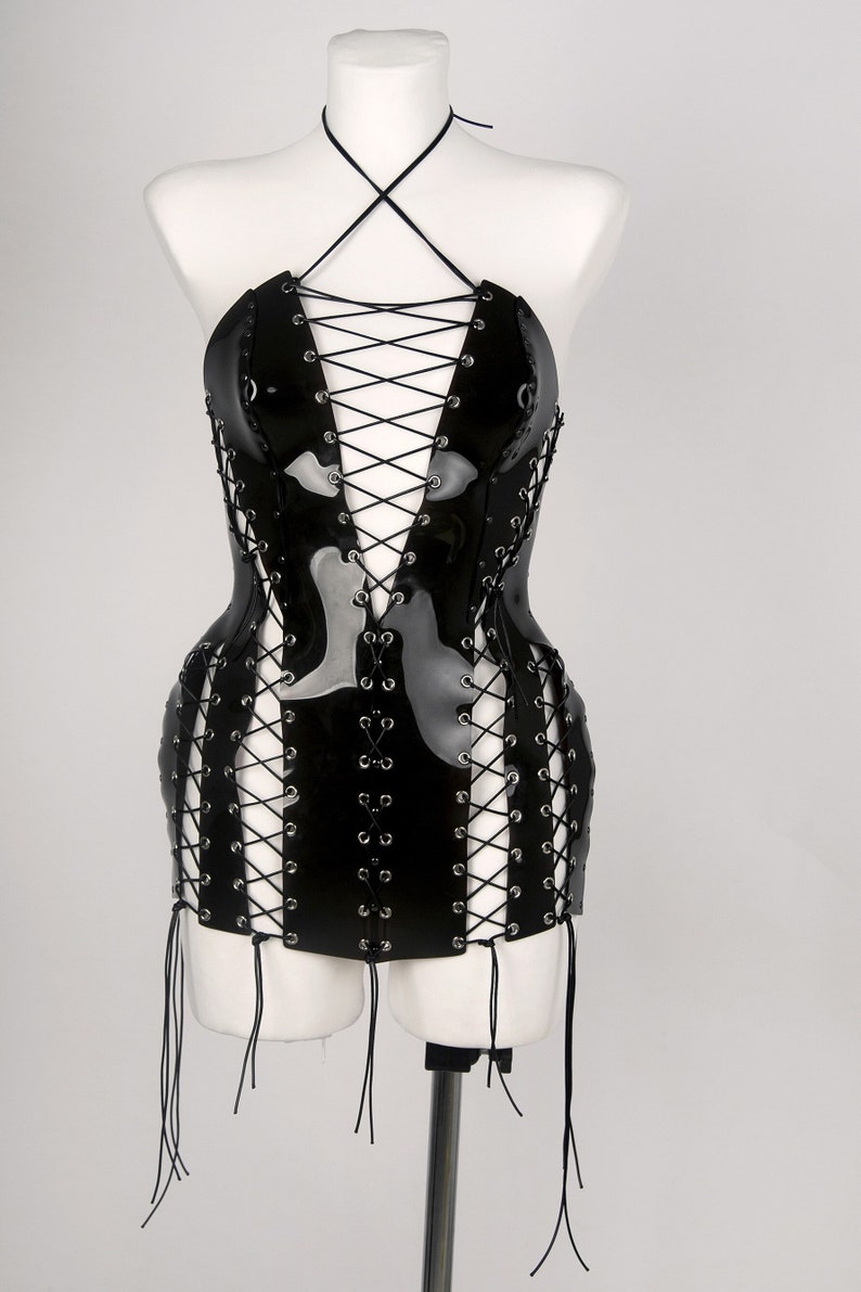 May include: A black patent leather mini dress with a lace-up front and a halter neckline. The dress has a fitted bodice and a flared skirt.