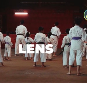 K&ouml;nnte beinhalten: Eine Gruppe von Kindern und Erwachsenen in wei&szlig;en Karate-Uniformen, einige mit farbigen G&uuml;rteln, &uuml;bt in einem Dojo. Das Wort "LENS" ist in gro&szlig;en wei&szlig;en Buchstaben &uuml;berlagert. Der Hintergrund ist ein rot get&ouml;nter Raum.