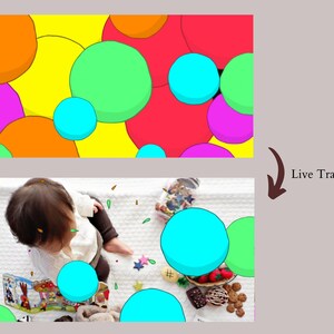 May include: A baby sits on a white blanket surrounded by colorful circles and confetti. The circles are blue, green, orange, pink, and yellow. The baby is wearing a white sweater and brown pants. The text "Live Transitions" is visible in the image.