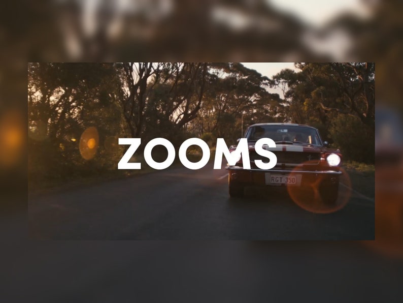 May include: A vintage red car with white racing stripes drives down a tree-lined road. The word "ZOOMS" is displayed in large white letters across the image. The car's headlights are on, and the license plate is visible.