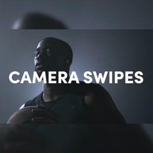 May include: A person in a black tank top with the text "CAMERA SWIPES" in white. The person is holding a basketball. The background is a dark gray.