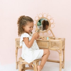 rattan kids vanity with stool and daisy shaped mirror. pink "be mine" banner on wall.