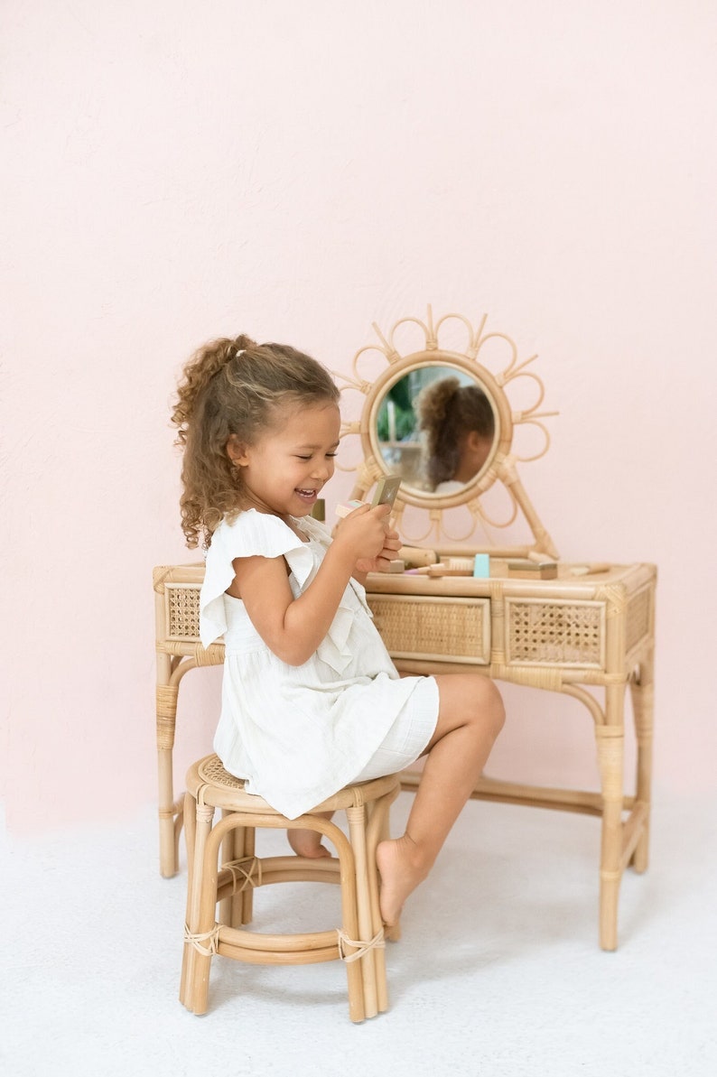 rattan kids vanity with stool and daisy shaped mirror. pink "be mine" banner on wall.