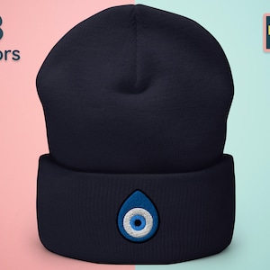 May include: A navy blue beanie with a white and blue evil eye design. The beanie is made of a soft, comfortable material and is perfect for keeping your head warm in the winter.