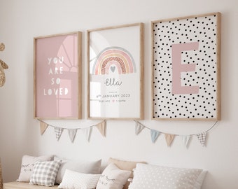 Puede incluir: Tres impresiones enmarcadas en una pared blanca. La impresión de la izquierda dice "You are so loved" en letras rosas sobre un fondo rosa. La impresión del medio presenta un arcoíris con un corazón rosa y el nombre "Ella" en letras blancas. La impresión de la derecha tiene una gran letra rosa "E" sobre un fondo blanco con lunares negros.