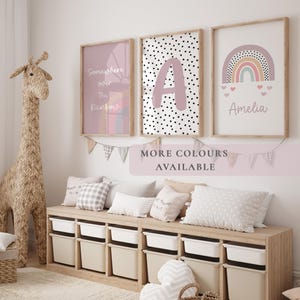 May include: A child's bedroom featuring framed wall art, a giraffe sculpture, and storage bins. The art includes a rainbow, initial, and text. The colour scheme is soft pink, white, and beige. The text on the art says "Somewhere over the Rainbow", "A", and "Amelia".