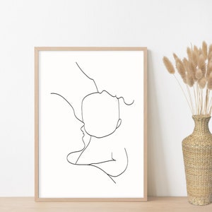 Puede incluir: Un dibujo en blanco y negro de una l&iacute;nea de un padre sosteniendo un beb&eacute;. El dibujo es de estilo simple y minimalista y est&aacute; enmarcado en un marco de madera claro.