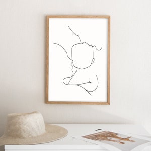 Puede incluir: Un dibujo en blanco y negro de una l&iacute;nea de un padre sosteniendo un beb&eacute;. El dibujo es de estilo simple y minimalista y est&aacute; enmarcado en un marco de madera claro.
