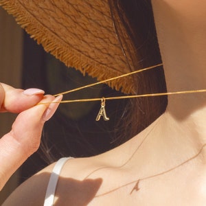 May include: A gold chain necklace with a gold letter 'A' pendant.