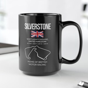Könnte beinhalten: Schwarze Keramik-Tasse mit dem Wort "SILVERSTONE" in Weiß, einer Union Jack und einer Streckenkarte. Darunter steht "NORTHAMPTONSHIRE, UNITED KINGDOM" und "HOME OF BRITISH MOTOR RACING".