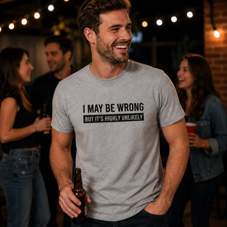May include: A heather gray short-sleeved crew neck t-shirt featuring the black printed text I MAY BE WRONG BUT IT'S HIGHLY UNLIKELY. The shirt is made of a soft cotton-blend fabric and has a standard fit with a straight hemline and short sleeves.
