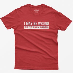 May include: A red short-sleeved t-shirt featuring the white text I MAY BE WRONG BUT IT'S HIGHLY UNLIKELY printed across the chest. The shirt has a crew neckline and a label inside the collar area with the text OSCAR MODS 100% COTTON MADE IN USA.