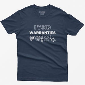 May include: A navy blue t-shirt with the text "I VOID WARRANTIES" in white. The shirt features a row of five white car part icons: a turbocharger, a spark plug, a steering wheel, and two exhaust pipes.