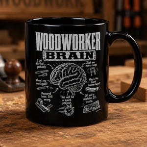 Peut inclure: Un mug en céramique noire avec un graphique blanc représentant un cerveau humain entouré de textes et d'illustrations sur le thème du travail du bois, incluant WOODWORKER BRAIN, un serre-joint, un crayon, un mètre ruban et un chronomètre.