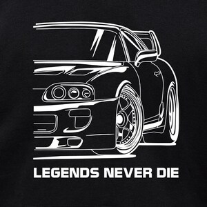 Puede incluir: Dibujo lineal blanco de un coche deportivo sobre fondo negro. Se ve el perfil delantero y lateral del coche, destacando sus faros, ruedas y aler&oacute;n. El texto "LEGENDS NEVER DIE" est&aacute; impreso en blanco debajo.