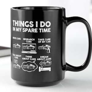 以下が含まれることがあります： THINGS I DO IN MY SPARE TIMEという白い文字が書かれた黒いセラミック製のマグカップ。その下に、DRIVE CARS、RESEARCH CARS、TAKE CARE OF MY CAR、TALK ABOUT CARS、THINK ABOUT CARS、DREAM ABOUT CARSというラベルが付いた6つの車のイラストが描かれています。