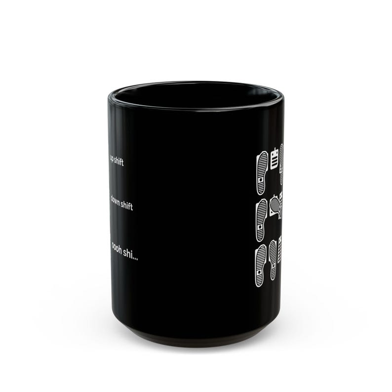 Puede incluir: Una taza de cer&aacute;mica negra con un gr&aacute;fico blanco de pies sobre pedales de coche. El texto dice up shift, down shift y oooh shi... junto a ilustraciones de posiciones de los pies en un pedal de embrague, freno y acelerador de transmisi&oacute;n manual.