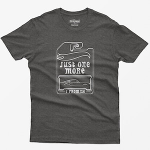 May include: A dark grey t-shirt with a white graphic of a car tag that says "Just one more I promise".