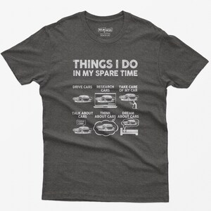 May include: A dark gray t-shirt with the text "Things I do in my spare time" and a list of car-related activities, including "Drive Cars", "Research Cars", "Take Care of My Car", "Talk About Cars", "Think About Cars", and "Dream About Cars". Each activity is illustrated with a cartoon car.