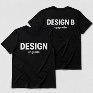 Pode incluir: Duas camisetas pretas de manga curta com gola redonda. A camiseta da frente apresenta o texto branco "DESIGN" em letras maiúsculas grandes com a palavra "upgrade" em letras menores abaixo. A camiseta de trás exibe "DESIGN B" e "upgrade".