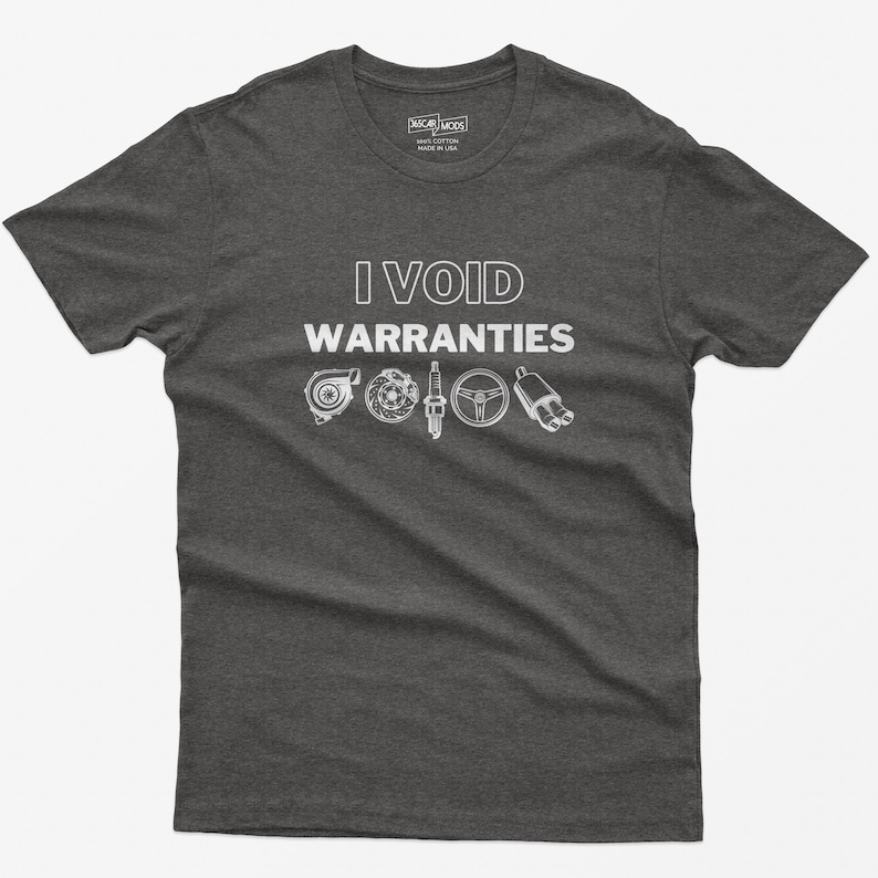 May include: A dark grey t-shirt with the text "I VOID WARRANTIES" in white. The shirt features a graphic of car parts, including a turbocharger, spark plugs, a steering wheel, and an exhaust pipe.