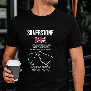 May include: A black t-shirt featuring the white text SILVERSTONE, a Union Jack flag, the location Northamptonshire, United Kingdom, established 1948, length 5.891 km - 3.660 mi, a white outline of the race track, and the text HOME OF BRITISH MOTOR RACING.