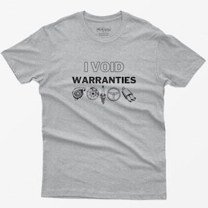 May include: A grey t-shirt with the text "I VOID WARRANTIES" in black. The text is surrounded by images of car parts, including a turbocharger, a spark plug, a steering wheel, and an exhaust pipe.