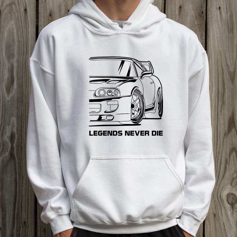 Puede incluir: Sudadera con capucha blanca con un gr&aacute;fico negro de un coche deportivo y el texto "LEGENDS NEVER DIE" debajo. El dise&ntilde;o del coche es un dibujo lineal detallado de la mitad delantera de un veh&iacute;culo.