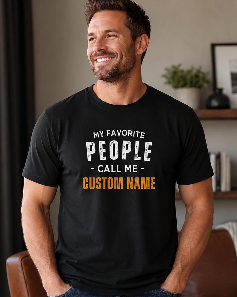 May include: A black short-sleeved t-shirt featuring the white text MY FAVORITE PEOPLE CALL ME and the orange text CUSTOM NAME printed on the chest. The shirt has a crew neckline and a standard fit, displaying a clear graphic design on the front.