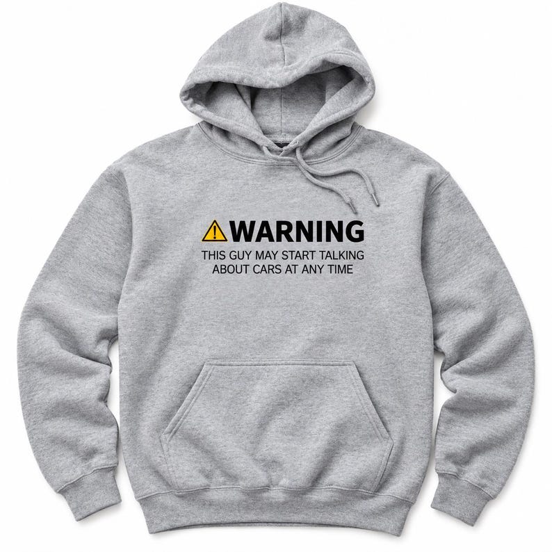 May include: A heather gray hooded sweatshirt featuring a front kangaroo pocket and a drawstring hood. The chest displays a yellow warning triangle icon followed by the black text: WARNING THIS GUY MAY START TALKING ABOUT CARS AT ANY TIME.