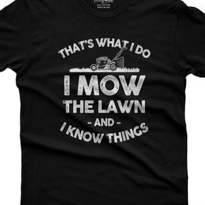 以下が含まれることがあります： 芝刈り機の白いグラフィックと「THAT'S WHAT I DO I MOW THE LAWN - AND - I KNOW THINGS」というテキストがプリントされた黒の半袖Tシャツ。首元の内側のラベルには「365CAR MODS 100% COTTON MADE IN USA」と記載されています。