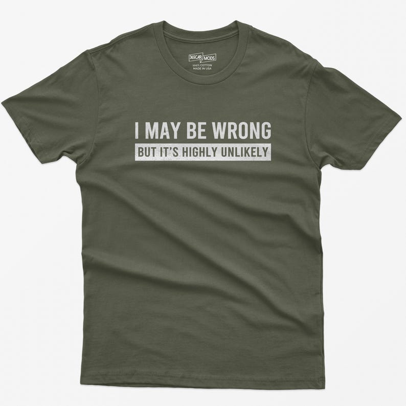 May include: An olive green short-sleeve t-shirt featuring the white text "I MAY BE WRONG BUT IT'S HIGHLY UNLIKELY" printed across the chest. The shirt has a crew neckline and a label inside the collar indicating 100% cotton and made in the USA.