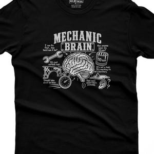 Puede incluir: Una camiseta negra con un gráfico blanco de un cerebro humano rodeado de ilustraciones de temática mecánica y texto que incluye "MECHANIC BRAIN", "I can fix that", "Has anyone seen my 10 mm?", "It's just surface rust" y "Should take about an hour."