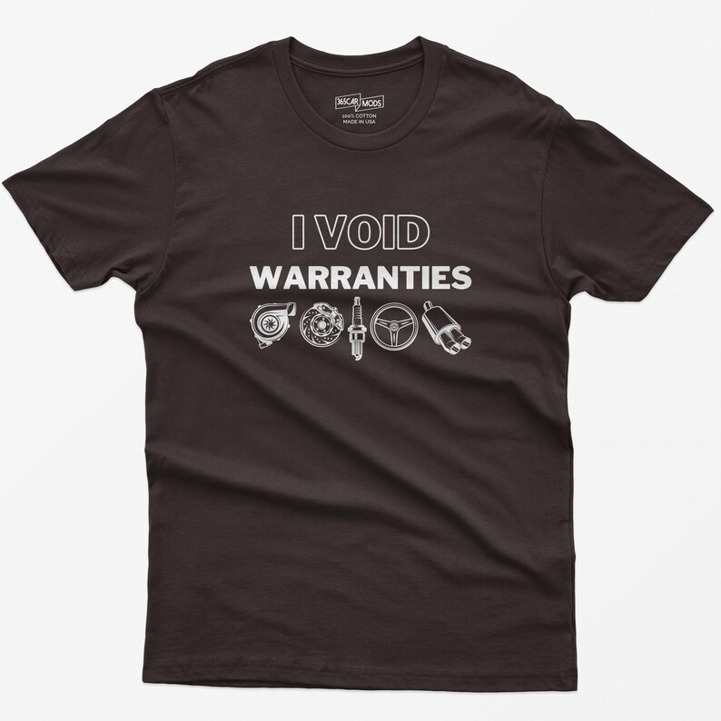May include: A dark grey t-shirt with the text "I VOID WARRANTIES" in white. The shirt features a graphic of car parts, including a turbocharger, spark plug, steering wheel, and exhaust pipe.