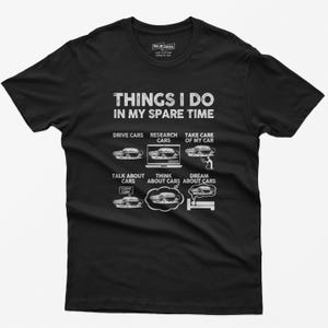 May include: Black t-shirt with white text that reads "Things I do in my spare time". The text is surrounded by illustrations of cars and car-related activities, including driving, researching, taking care of, talking about, thinking about, and dreaming about cars.