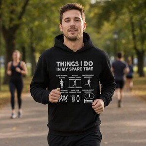 May include: A black hooded sweatshirt featuring white text that reads THINGS I DO IN MY SPARE TIME, accompanied by six graphic icons depicting running-related activities including planning routes, watching videos, and tracking progress.