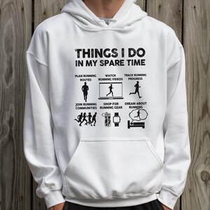May include: A white hooded sweatshirt featuring black text and graphics that read: THINGS I DO IN MY SPARE TIME, with icons and labels for planning routes, watching videos, tracking progress, joining communities, shopping for gear, and dreaming about running.
