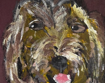 Pode incluir: Pintura em close-up do rosto de um cão, com pinceladas castanhas, amarelas e brancas. O cão tem olhos escuros, um nariz preto e uma língua rosa. O fundo é de cor castanho escuro.