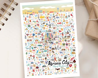 Puede incluir: Un mapa ilustrado y colorido de Kansas City, Missouri, con monumentos e iconos. El mapa incluye el texto "Kansas City, City of Fountains" y está rodeado por un cuaderno y una taza de café.