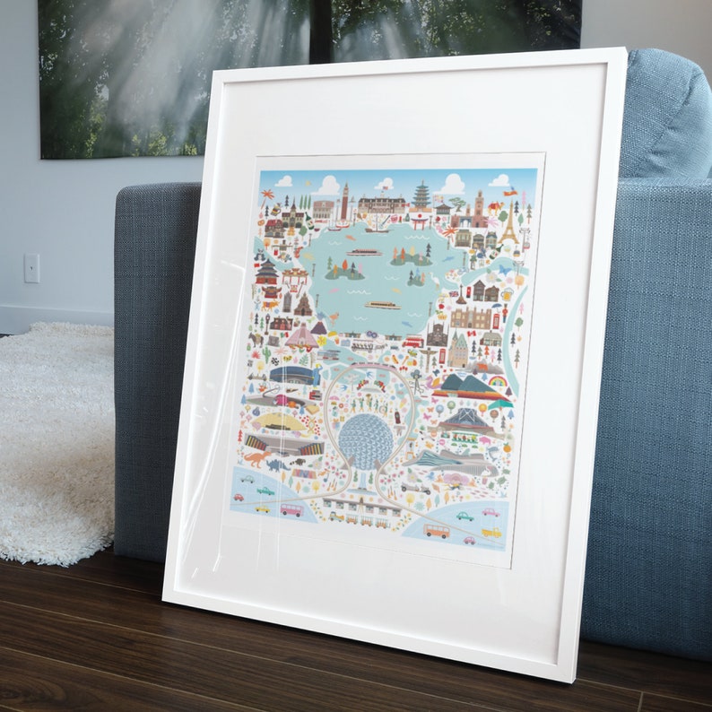 May include: A white framed print of a colorful illustrated map of a city. The map features buildings, landmarks, and transportation. The map is surrounded by a white border.