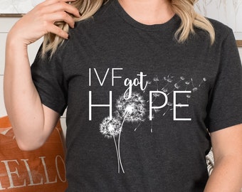 May include: A dark grey t-shirt with the text "IVF got HOPE" and a white dandelion graphic.