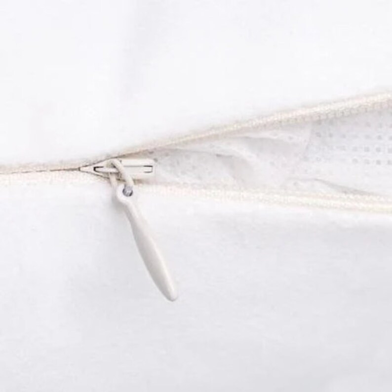 May include: Close-up of a white zipper on a pillowcase. The zipper is open and the zipper pull is white.