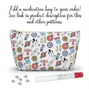 May include: White zippered pouch with a colorful pattern of fertility symbols, including sperm, eggs, a uterus, and a pregnancy test. The pouch is sitting on a white surface next to a white pen and several white pills.