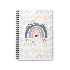 May include: A white spiral notebook with a rainbow pattern and the text "waiting for a rainbow" on the cover.